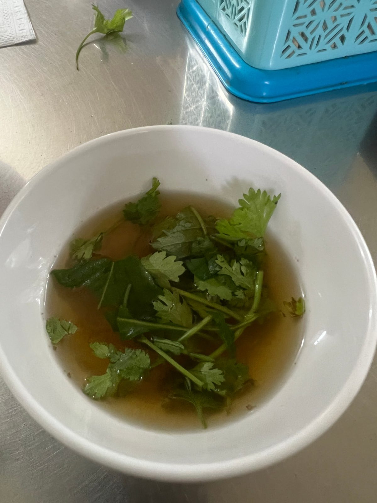 Bowl of dipping broth with fresh cilantro at a food tour stop in Hanoi