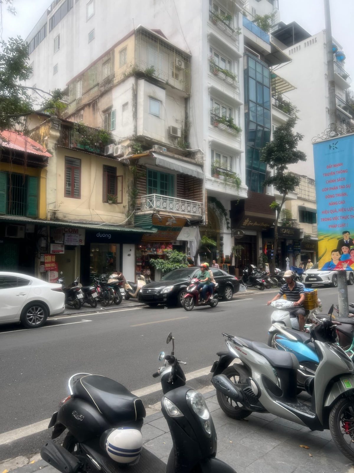Hanoi street scene with mopeds, cars and shopfronts in the Old Quarter