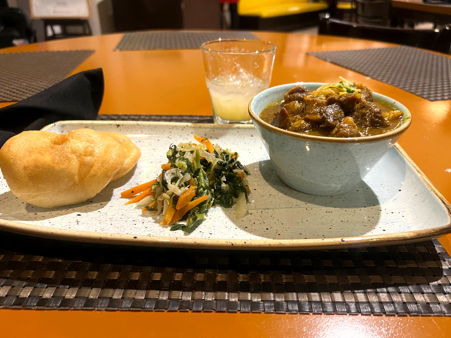 Oxtails in a bowl with fried dumpling and steamed cabbage and callaloo on a plate at Urban Heatz by Flavor