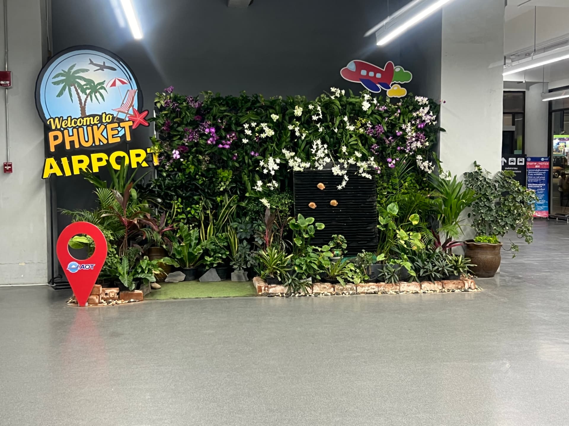 Welcome to Phuket Airport sign with a tropical plant display