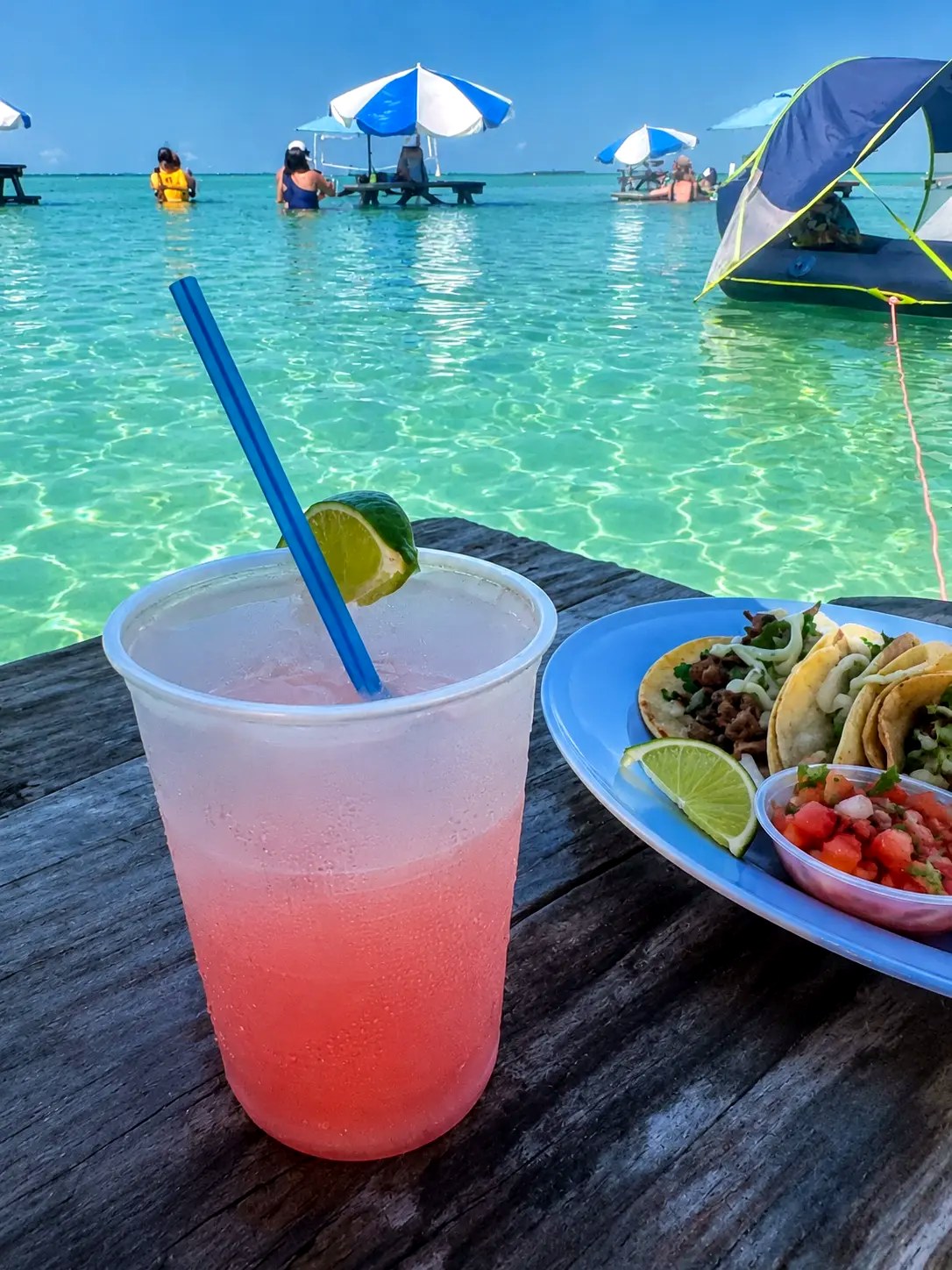 Blackened fish tacos and a strawberry daiquiri on a wooden table over the water at Blue Bayou, Secret Beach, Belize