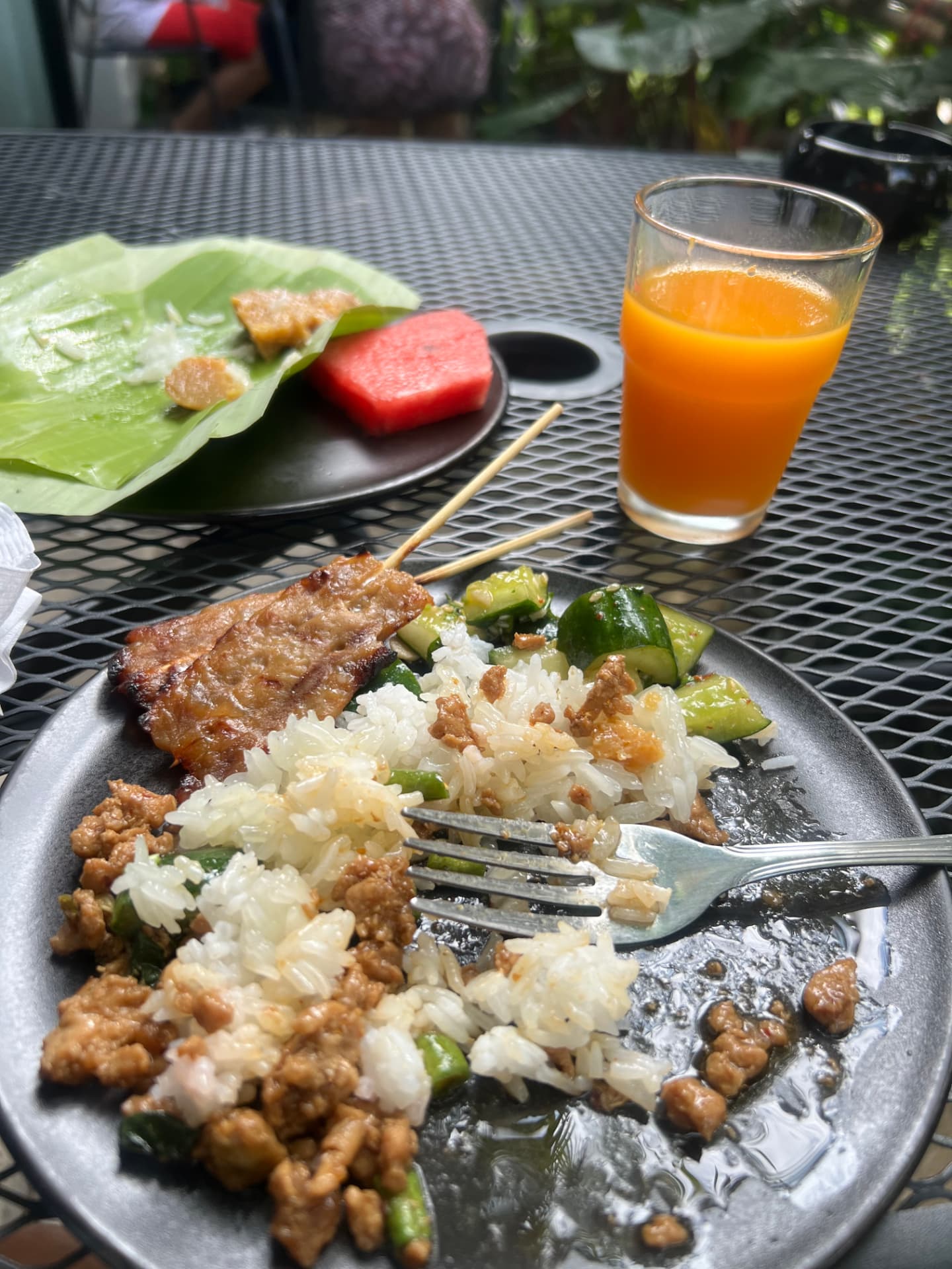 Thai breakfast at POR Arak with rice, pork skewers, cucumber salad, fresh watermelon and a glass of orange juice