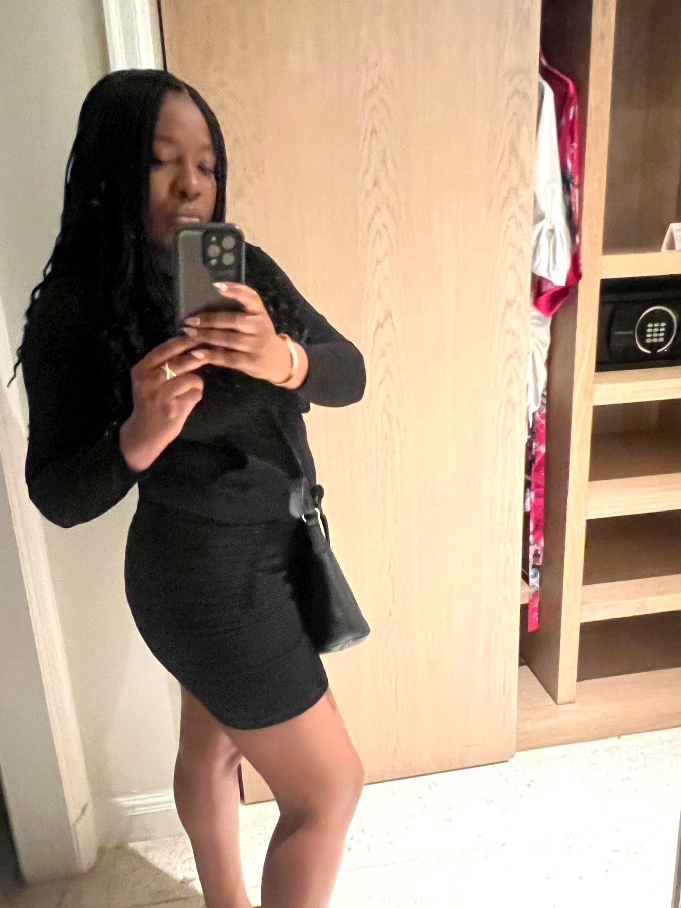 Me in a black dress taking a mirror photo in my room at the resort before heading out