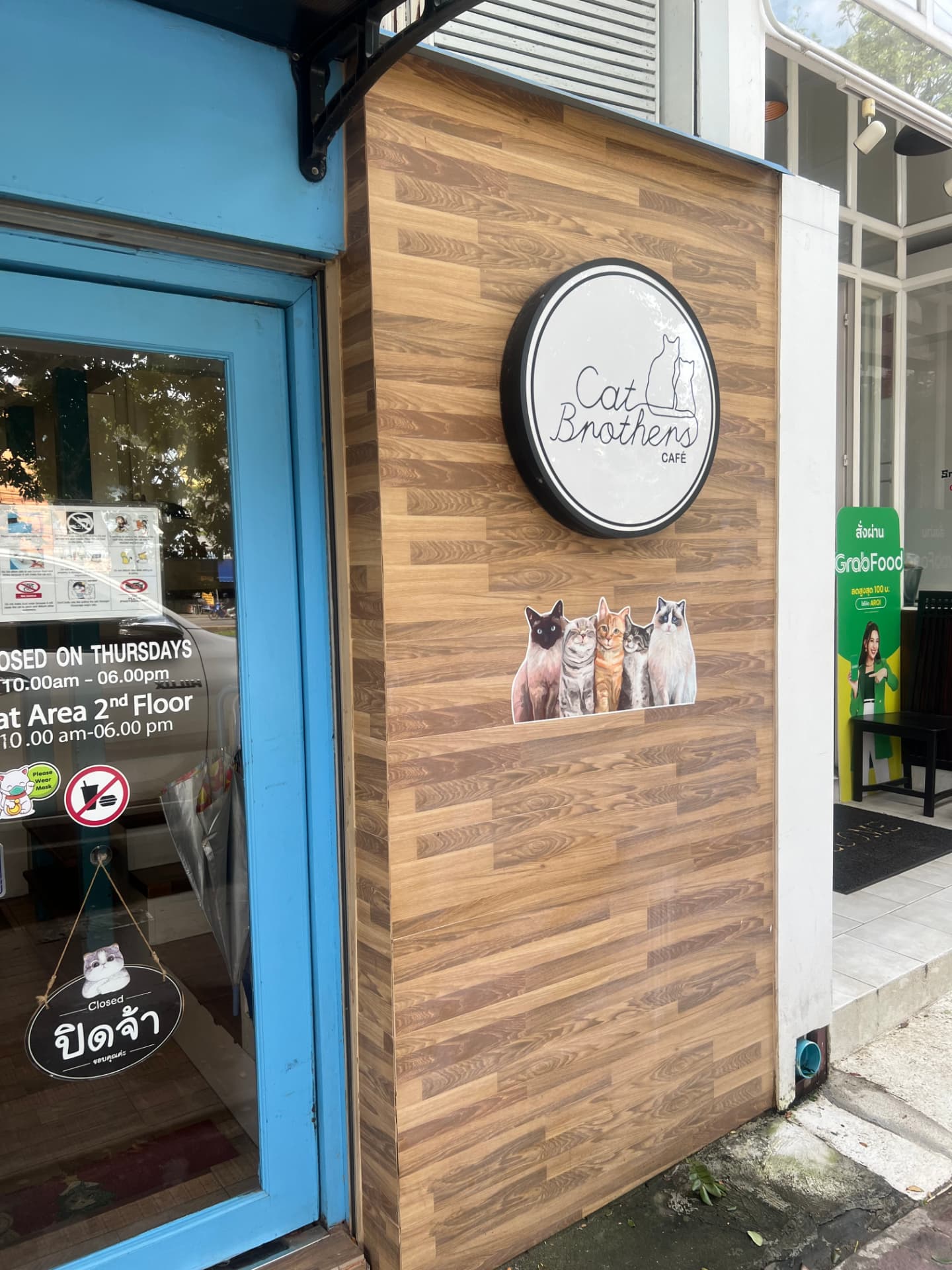 The wooden exterior and round Cat Brothers Cafe sign at the entrance of the cat cafe in Chiang Mai, Thailand