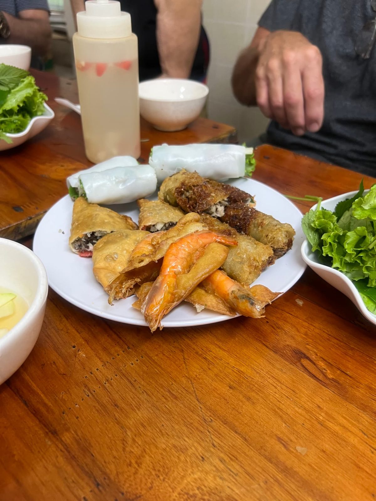 Plate of fried spring rolls, shrimp and fresh rolls with herbs
