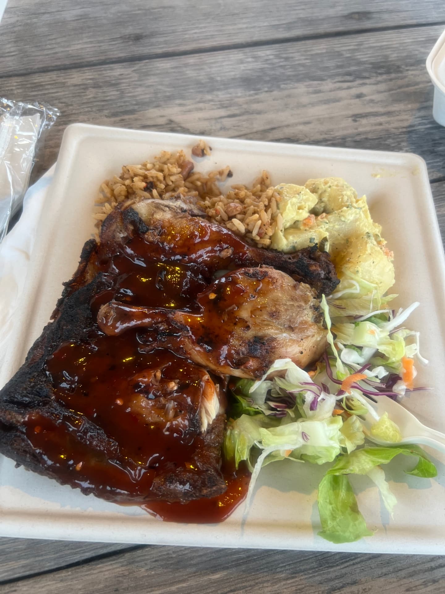 A plate of sauced grilled chicken with rice, potato salad and fresh salad from Shirley Heights