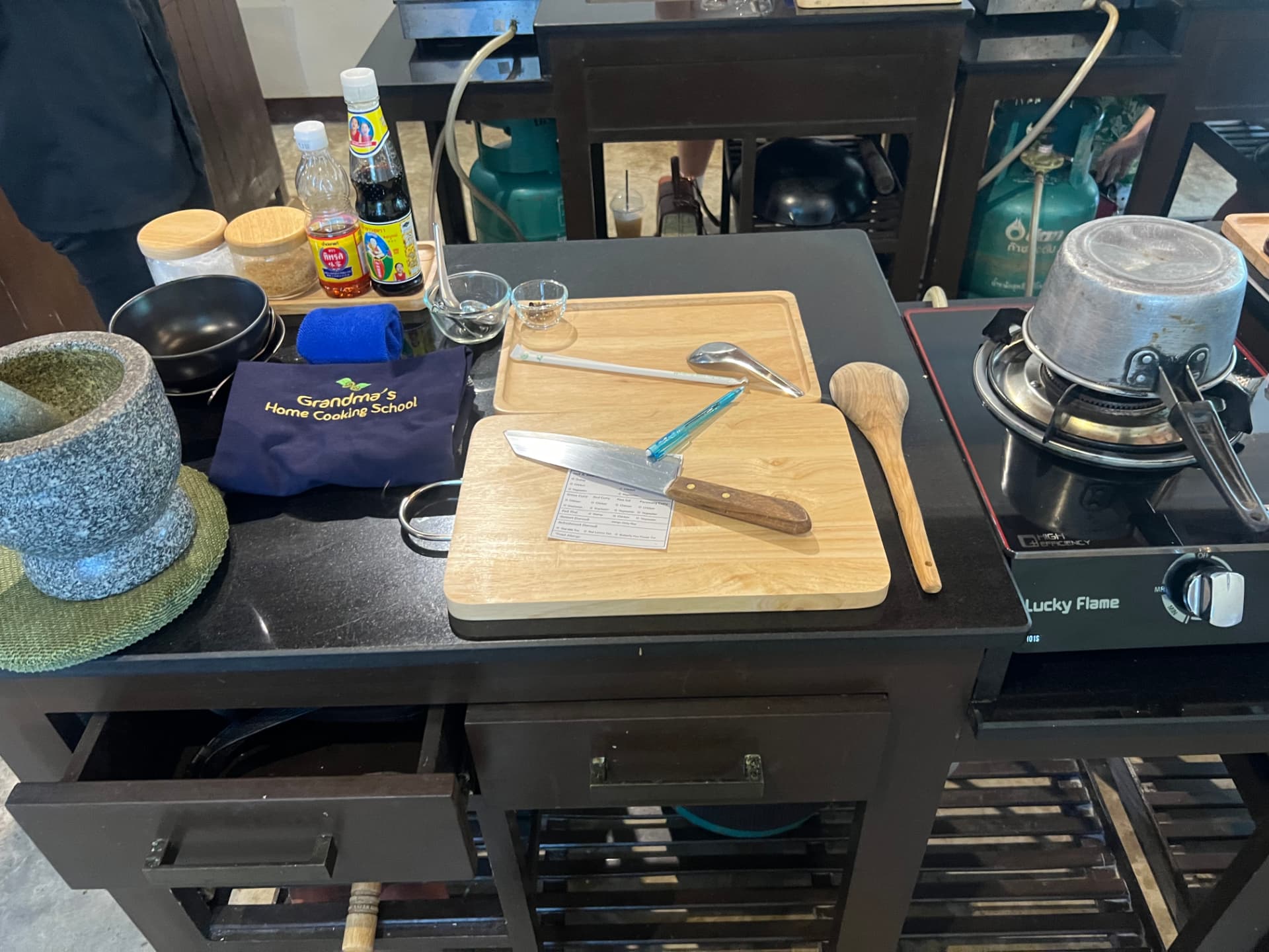 Individual cooking station with cutting board, knife, mortar and pestle, apron and gas burner at the Thai cooking school