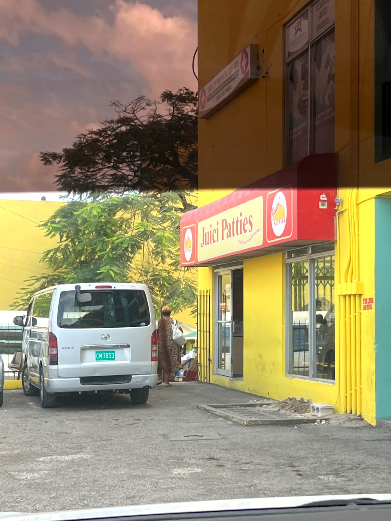 A bright yellow and red Juici Patties shop on a street corner in Jamaica