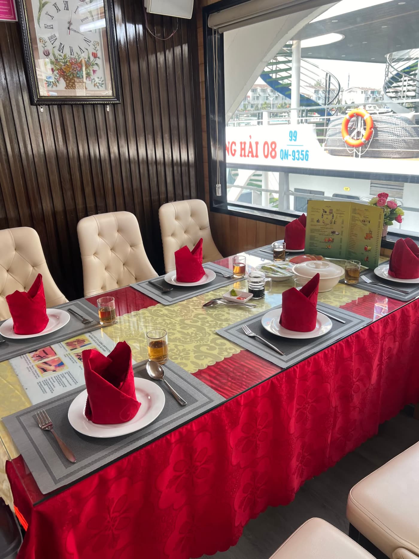 Table set with red napkins and dishes in the dining room of a Ha Long Bay cruise boat