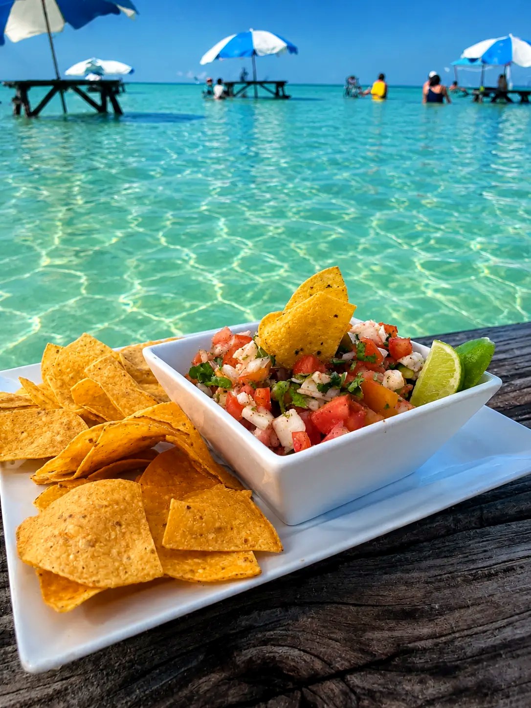 Shrimp ceviche with tortilla chips on a table at the edge of the turquoise water at Blue Bayou, Secret Beach, Belize