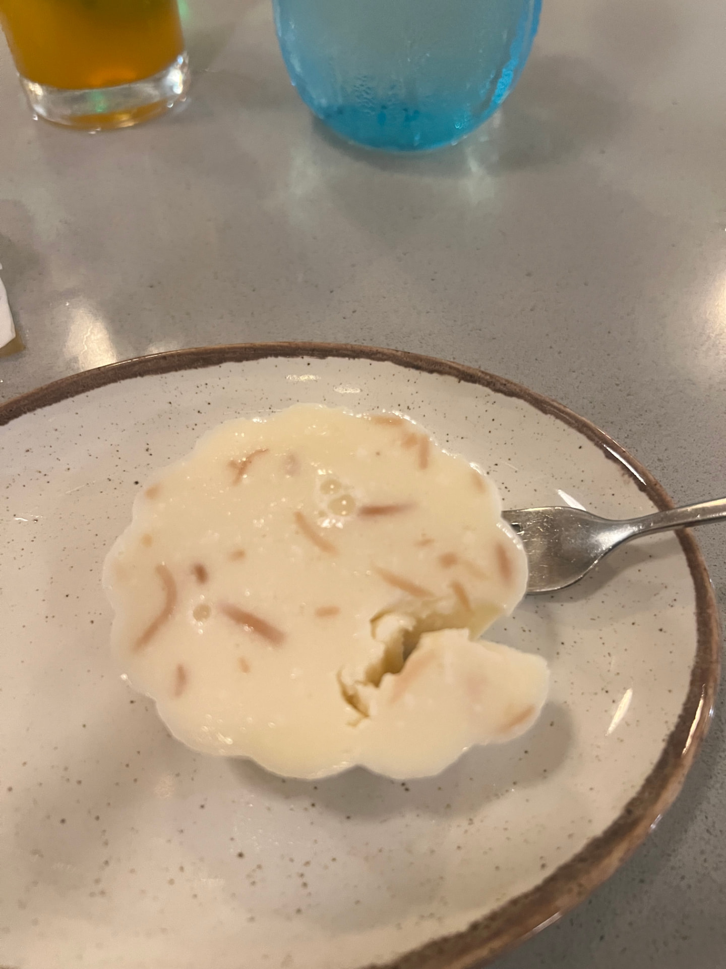 A creamy coconut dessert in a small speckled bowl with a fork at Haven Grill in Antigua
