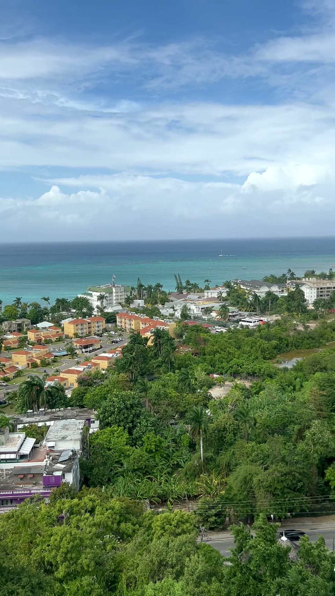 View over the Jamaican coastline — turquoise water, rooftops and green hills