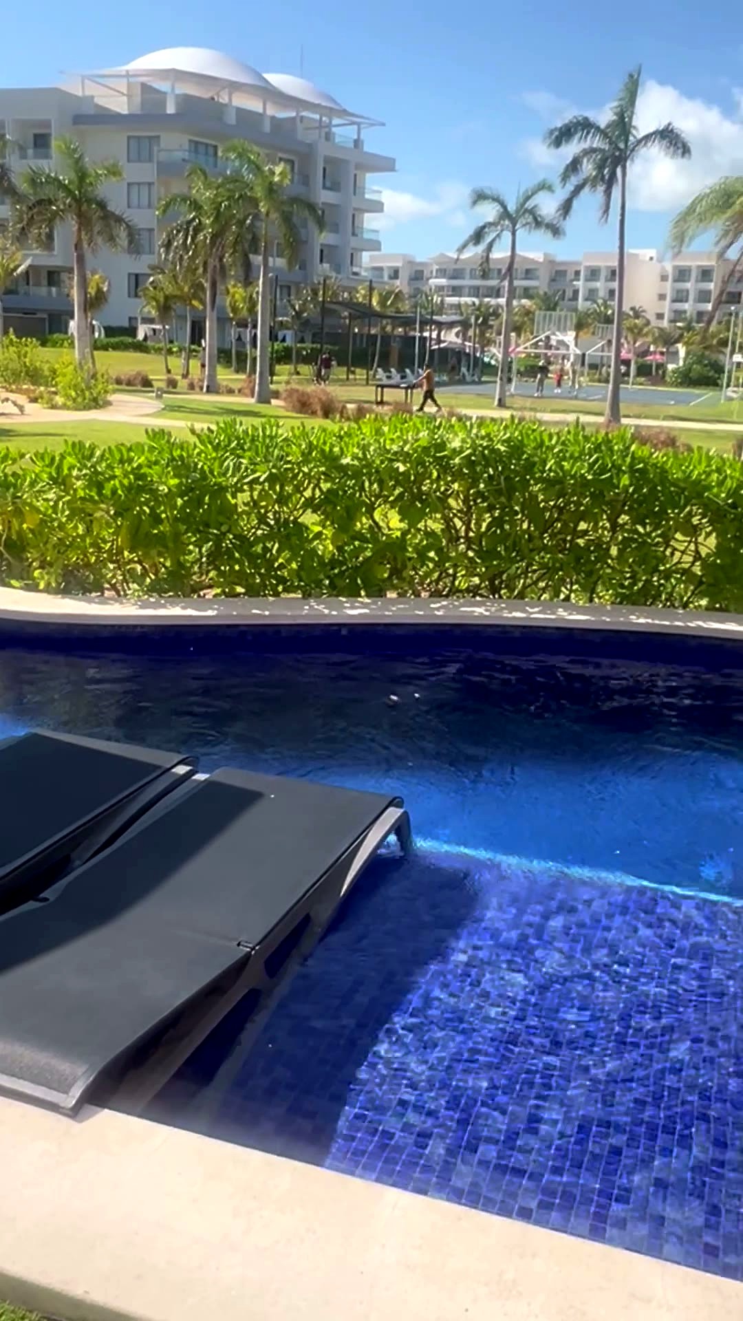 Morning light on my private swim-up pool with loungers, palm trees and the resort grounds behind it