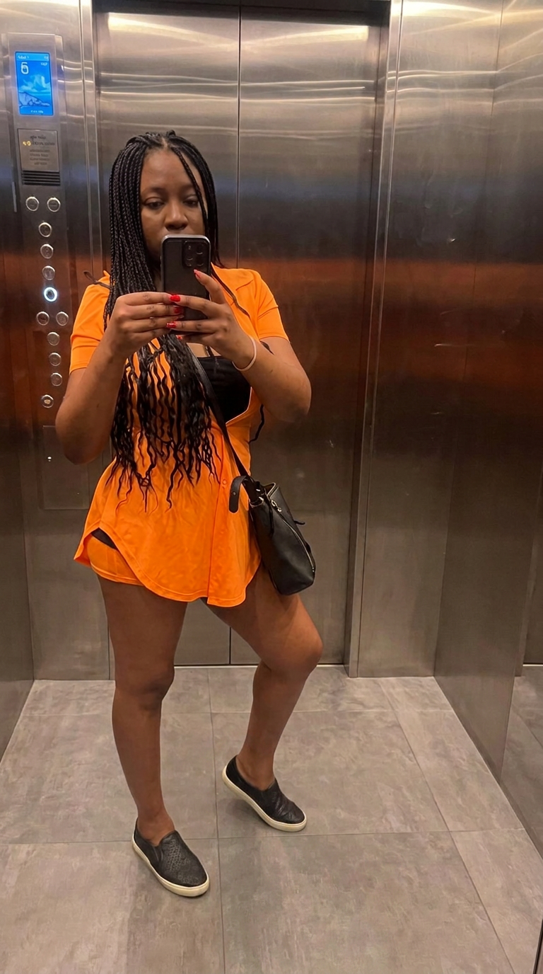 Jenn in an orange shirt dress taking a mirror photo in the elevator at her Chiang Mai hotel