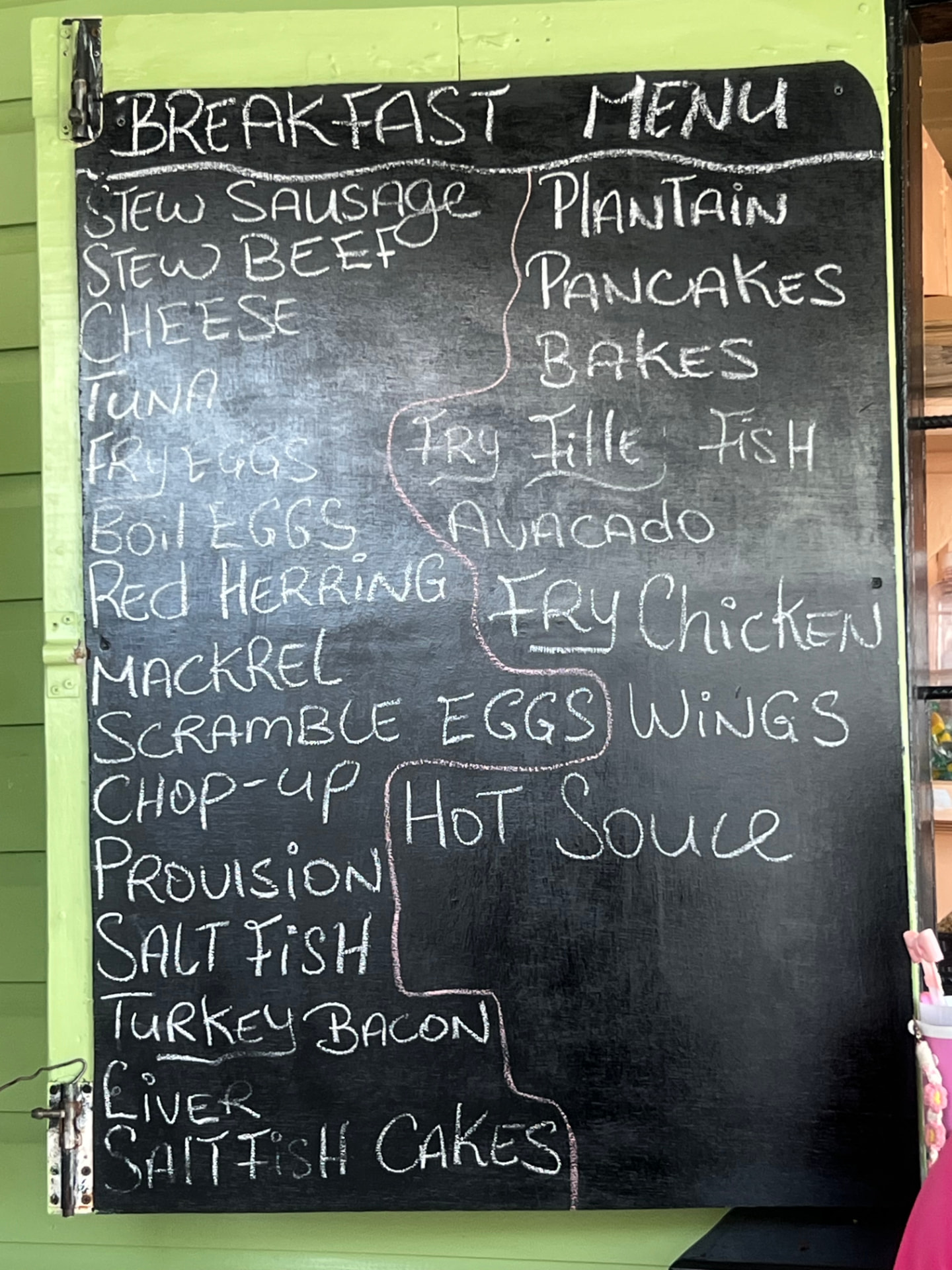 A chalkboard breakfast menu in Antigua listing saltfish, chop-up, stew beef, bakes, plantain and more