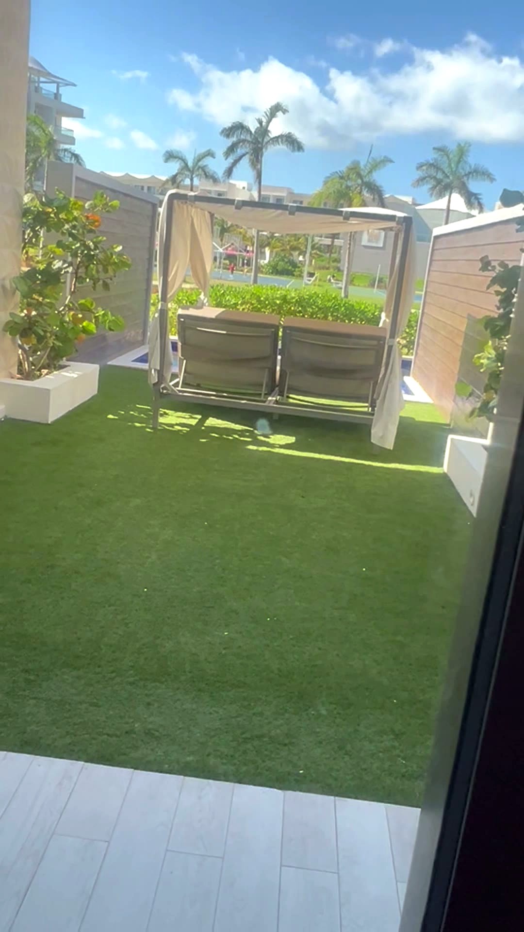 The patio outside my suite with a canopied daybed on the lawn beside the swim-up pool