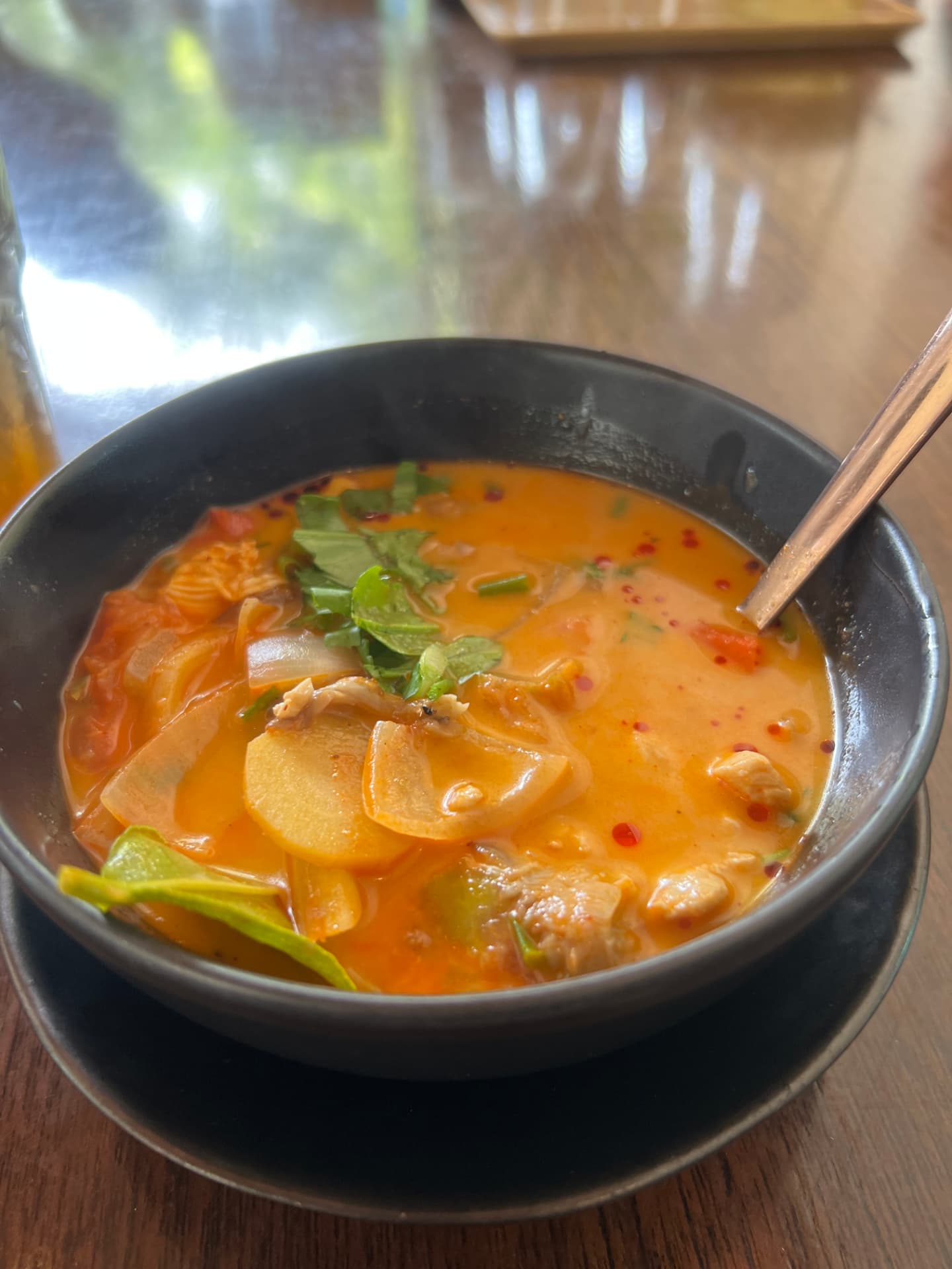 Bowl of homemade tom yum soup with chicken, tomato, mushrooms and cilantro made at the Chiang Mai cooking class