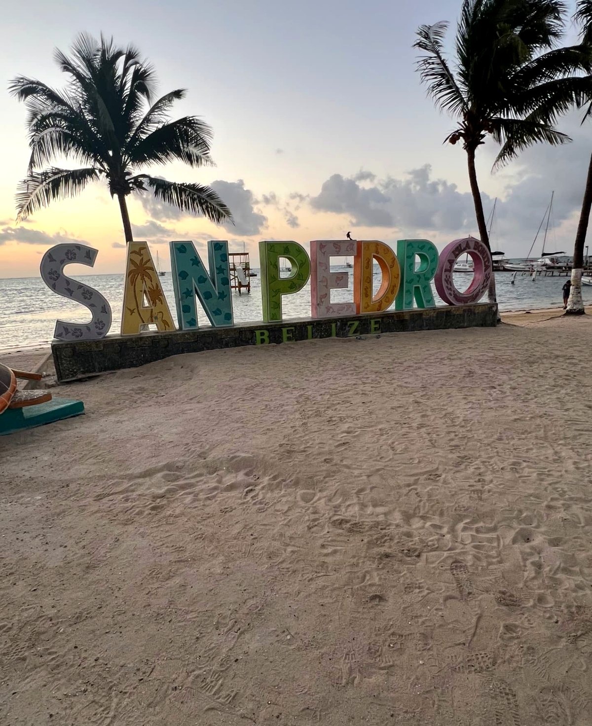 The San Pedro Belize sign on the beach at sunset with palm trees
